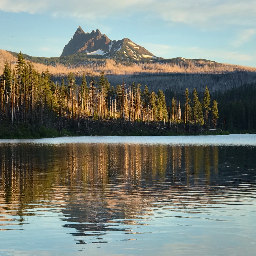 Mountain lake with jagged peak and forest reflections